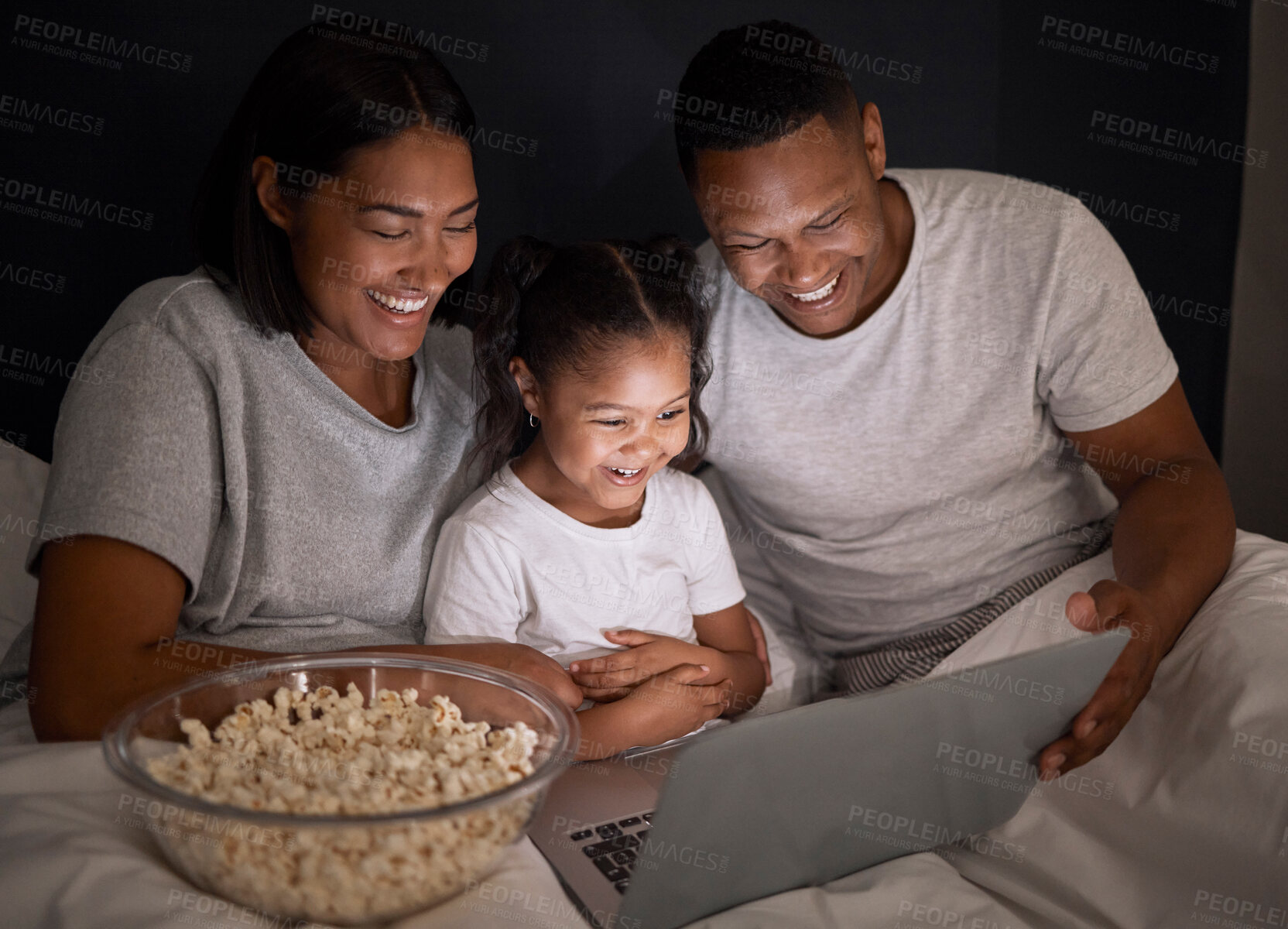 Buy stock photo Happy family, night and popcorn with laptop in bedroom for chill, unwind and weekend relax for movies. Mother, father and child in dark home with internet for streaming, videos and cartoon film.