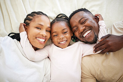 Buy stock photo Black family, portrait and happy kid in bedroom with parents to relax together in home above. Face, African mother and father with girl child in top view for bonding, laughing and embrace for support