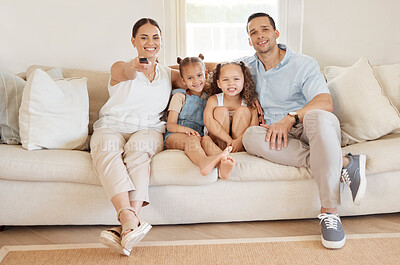Buy stock photo Shot of a woman using a tv remote while watching something at home with her family