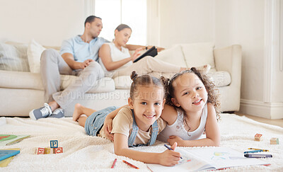 Buy stock photo Shot of two little girls doing artwork while their parents sit in the background