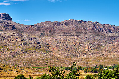 Buy stock photo Natural landscape view of mountain in nature. Scenic look of rocky hills and grassy terrain on a sunny day in the outdoors. Big blue sky background with greenery and small separated clouds outside.