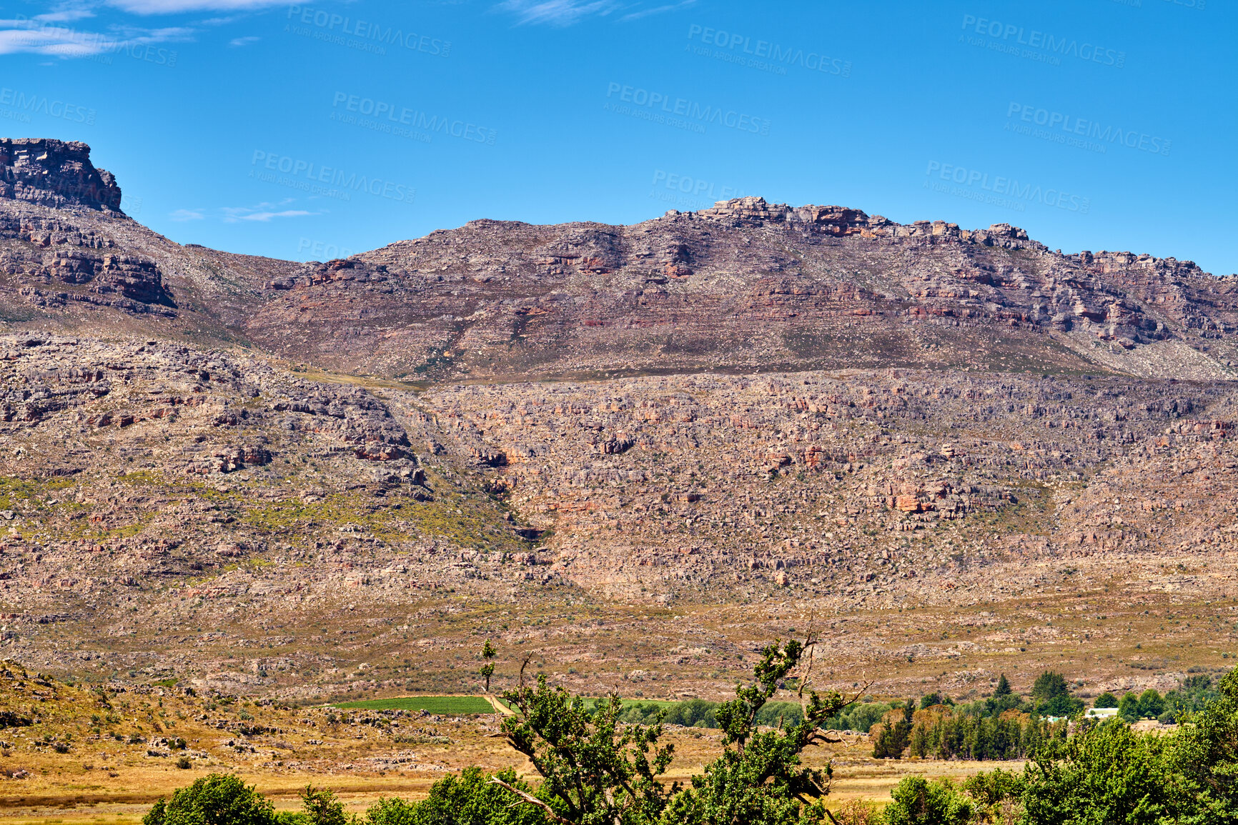 Buy stock photo Natural landscape view of mountain in nature. Scenic look of rocky hills and grassy terrain on a sunny day in the outdoors. Big blue sky background with greenery and small separated clouds outside.