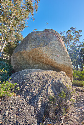 Buy stock photo Blue sky, weathered rock and cracked stone from heat exposure and wind erosion along a countryside dirt path. Landscape view of a trail leading to lush green forest or woods in remote nature reserve