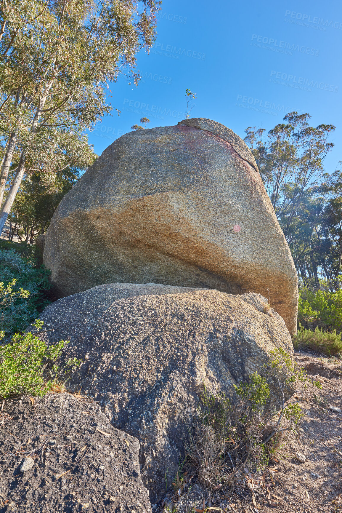 Buy stock photo Blue sky, weathered rock and cracked stone from heat exposure and wind erosion along a countryside dirt path. Landscape view of a trail leading to lush green forest or woods in remote nature reserve