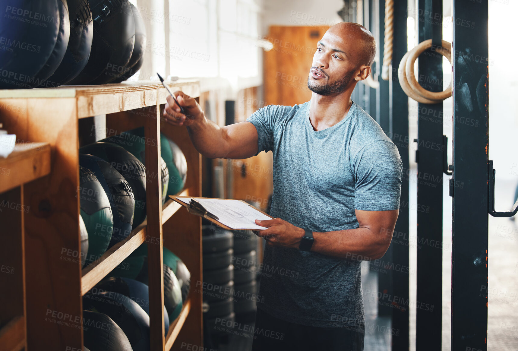 Buy stock photo Shot of a muscular young man using a clipboard while checking equipment in a gym