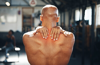 Buy stock photo Rearview shot of a muscular young man experiencing back pain while exercising in a gym