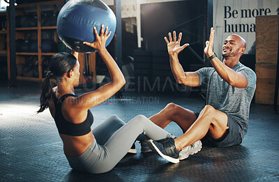 Buy stock photo Shot of a sporty young man and woman exercising together with a medicine ball in a gym