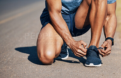 Buy stock photo Shot of a unrecognizable man tying his shoelaces outside