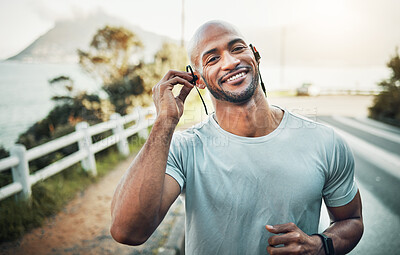 Buy stock photo Shot of a sporty young man wearing earphones while out for a workout