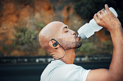 Buy stock photo Shot of a sporty young man drinking water while exercising outdoors