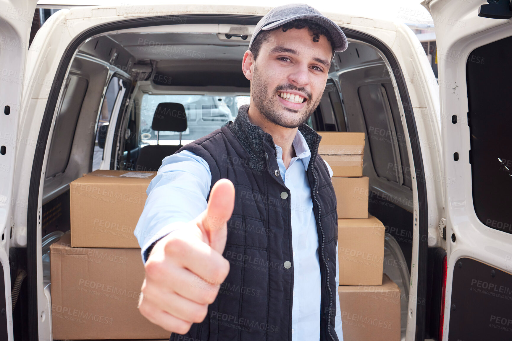 Buy stock photo Portrait of a young delivery man showing thumbs up while loading boxes from a van