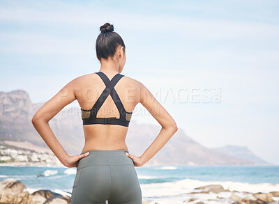 Buy stock photo Rearview shot of an unrecognizable athletic young woman standing with her hands on her hips during a workout on the beach