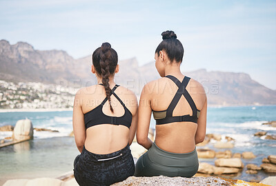 Buy stock photo Rearview shot of two unrecognizable athletic young women taking a break from their workout on the beach
