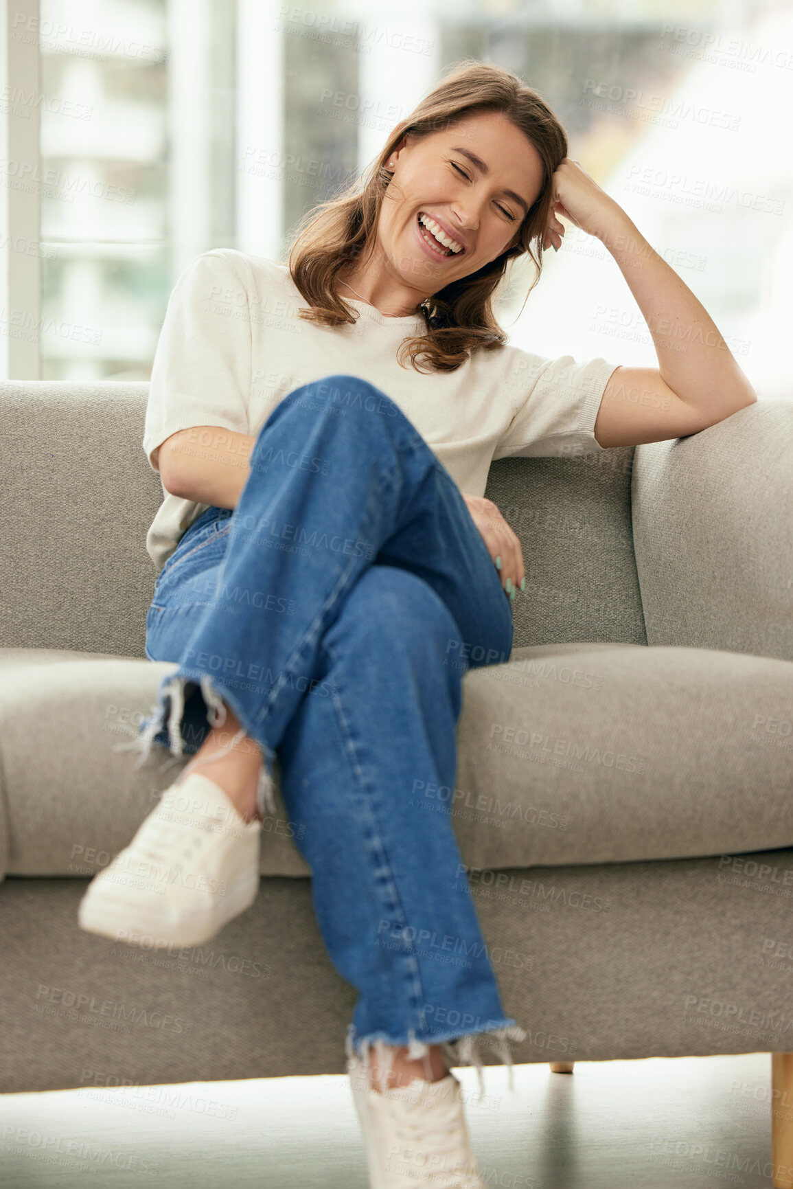 Buy stock photo Funny, smile and woman on sofa in home living room for relax, comedy or joke in apartment in Switzerland. Laughing, comic and happy girl on couch for comfort or excited in casual clothes in lounge