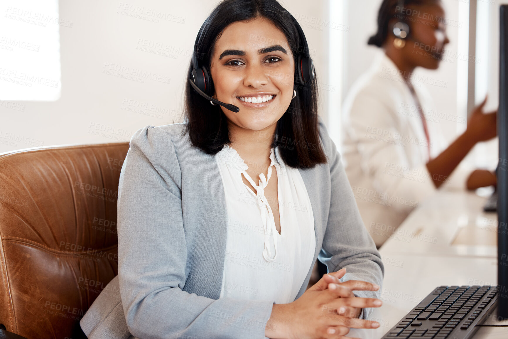 Buy stock photo Portrait of a young call centre agent working in an office with her colleague in the background