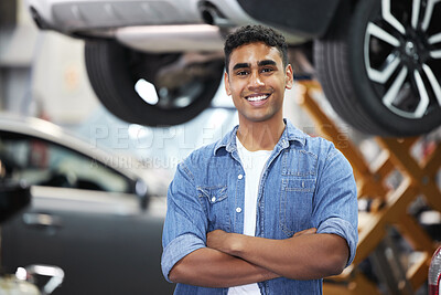 Buy stock photo Portrait of a handsome young mechanic standing with his arms folded in his workshop