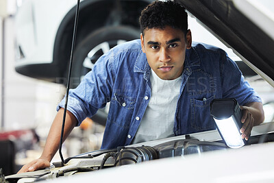 Buy stock photo Portrait of a handsome young male mechanic working on the engine of a car during a service