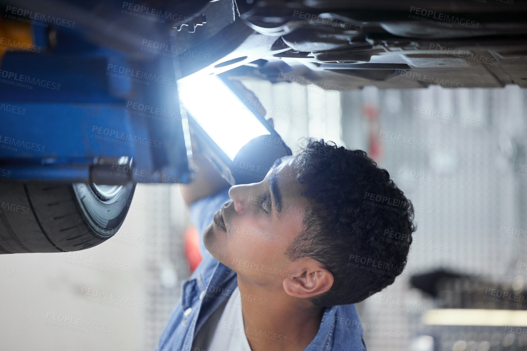 Buy stock photo Man, mechanic and bottom of car with light in workshop for working or maintenance, inspection and oil change. Person, motor and garage for engine or exhaust diagnostics, transmission and brake repair