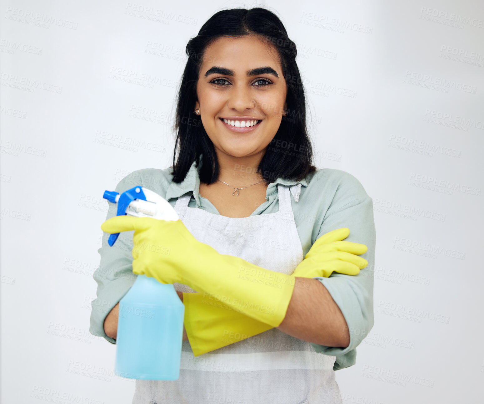 Buy stock photo Shot of a confident young woman standing with her arms crossed while cleaning at home