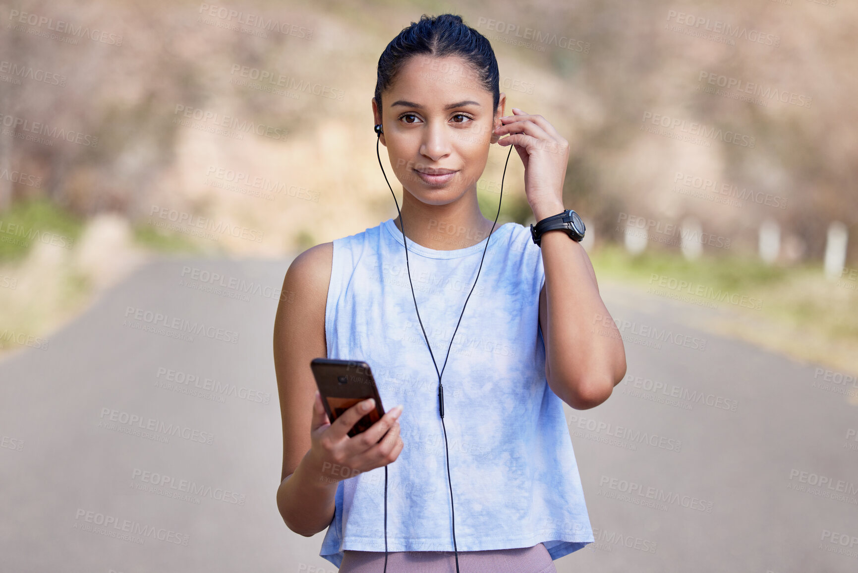 Buy stock photo Cropped shot of an attractive young female athlete setting up her playlist before starting her outdoor run