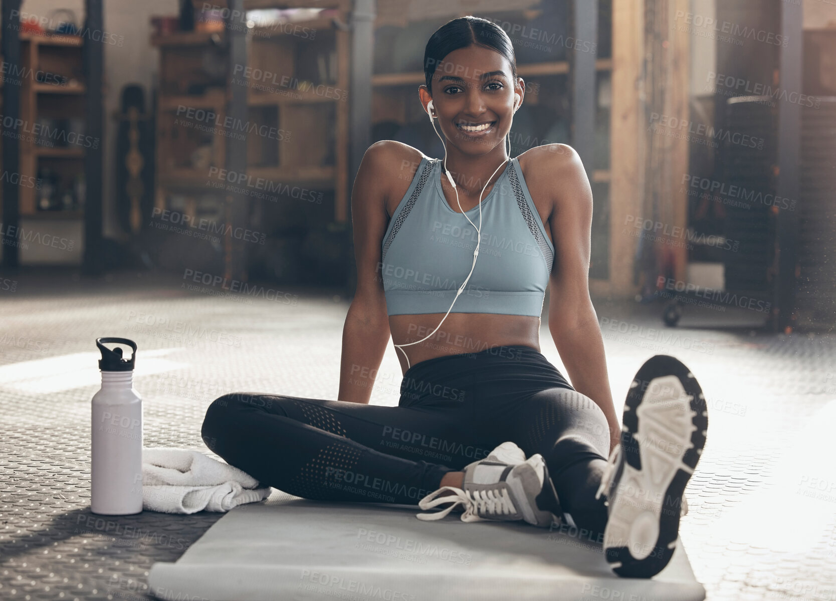 Buy stock photo Woman in gym, relax on mat with fitness and smile, workout with earphones, portrait and sports. Healthy, active with happy Indian female sitting in studio exercise with music, health and wellness