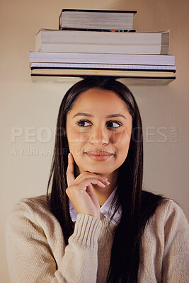 Buy stock photo Shot of a young woman looking thoughtful while posing with a stack of books on her head