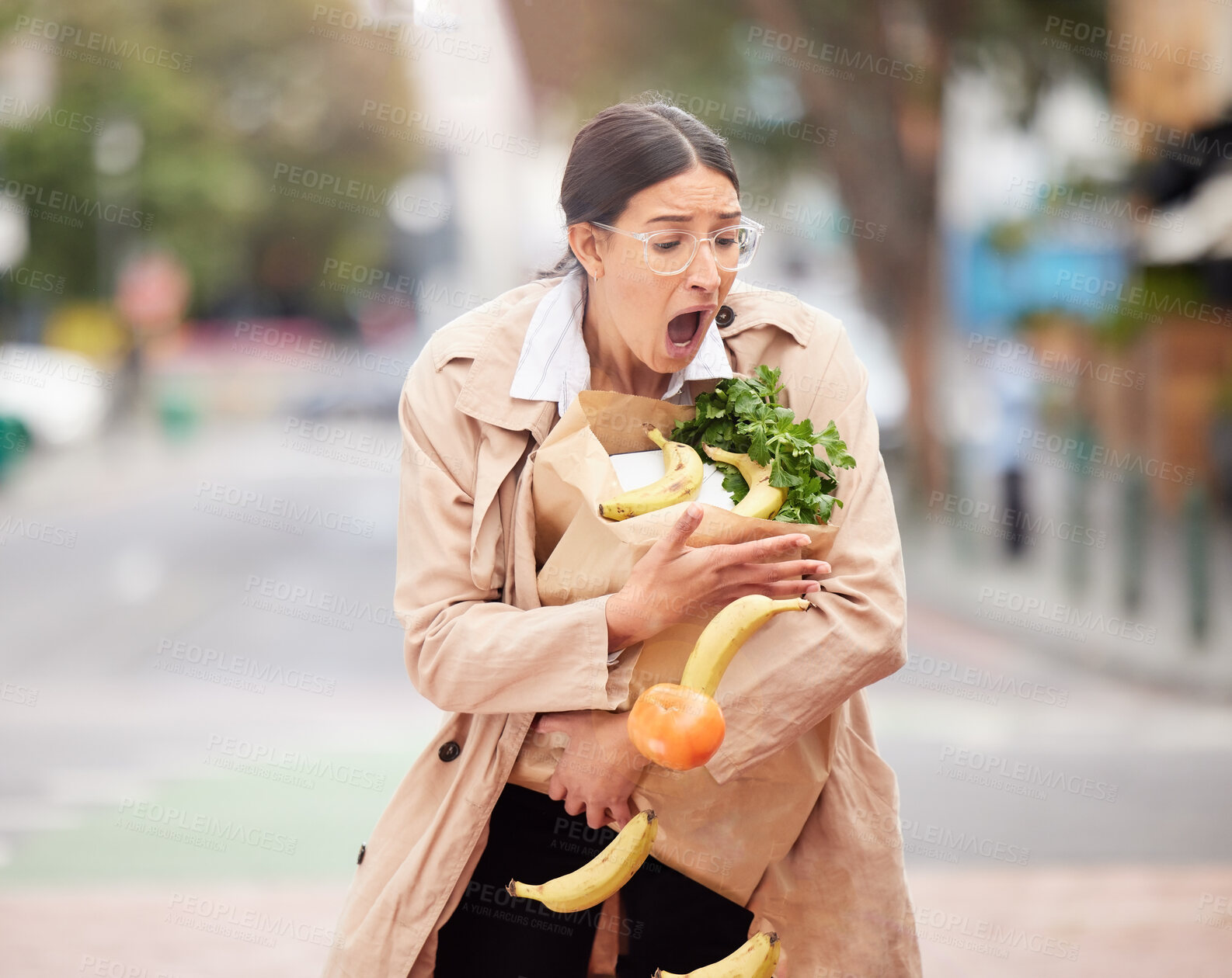 Buy stock photo Shot of a beautiful young woman trying to hold keep her groceries from falling from a broken paper bag