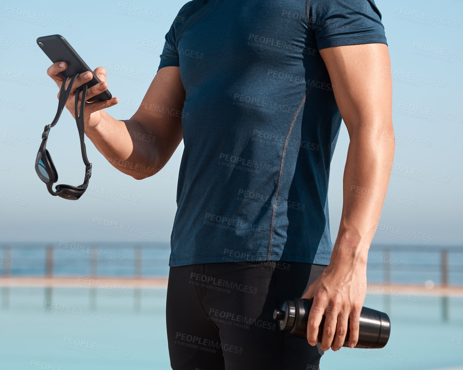 Buy stock photo Shot of an unrecognisable man using a smartphone before going for a swim