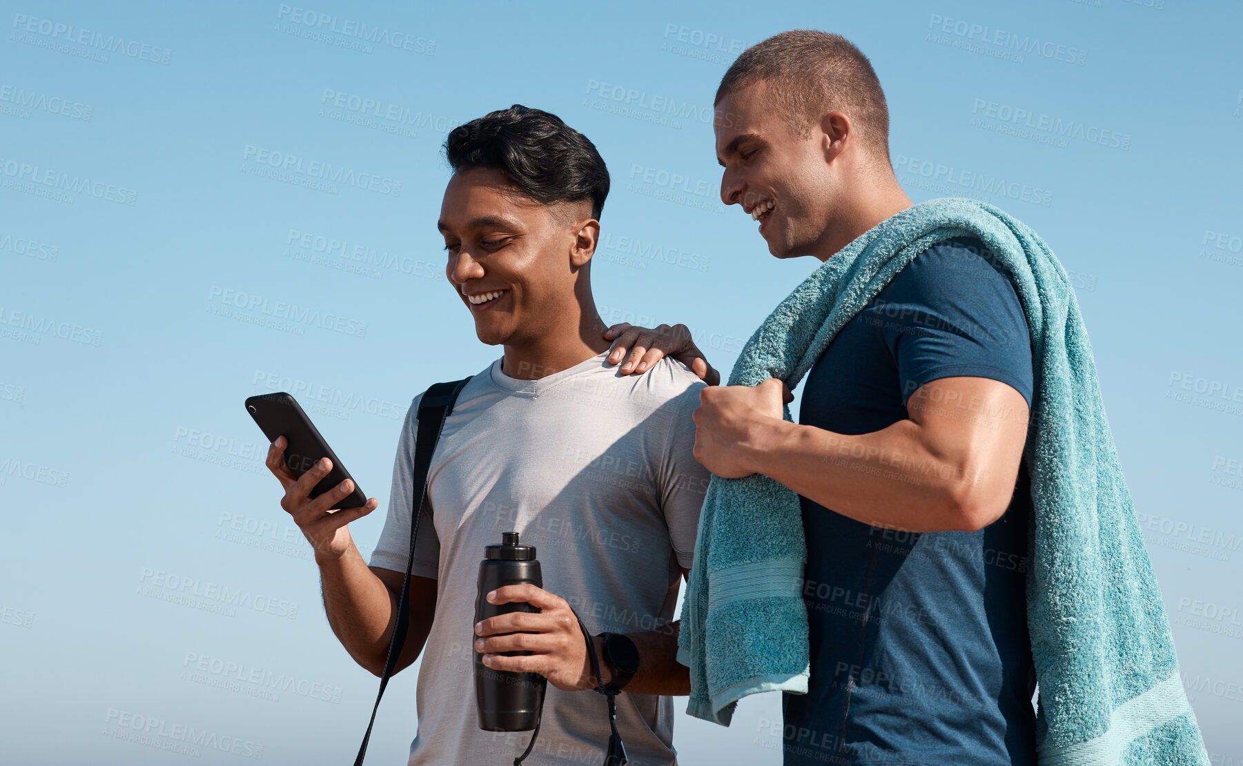 Buy stock photo Shot of two young men using a smartphone before going for a swim