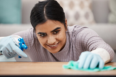 Buy stock photo Shot of a woman using a spray bottle and cloth while cleaning a table