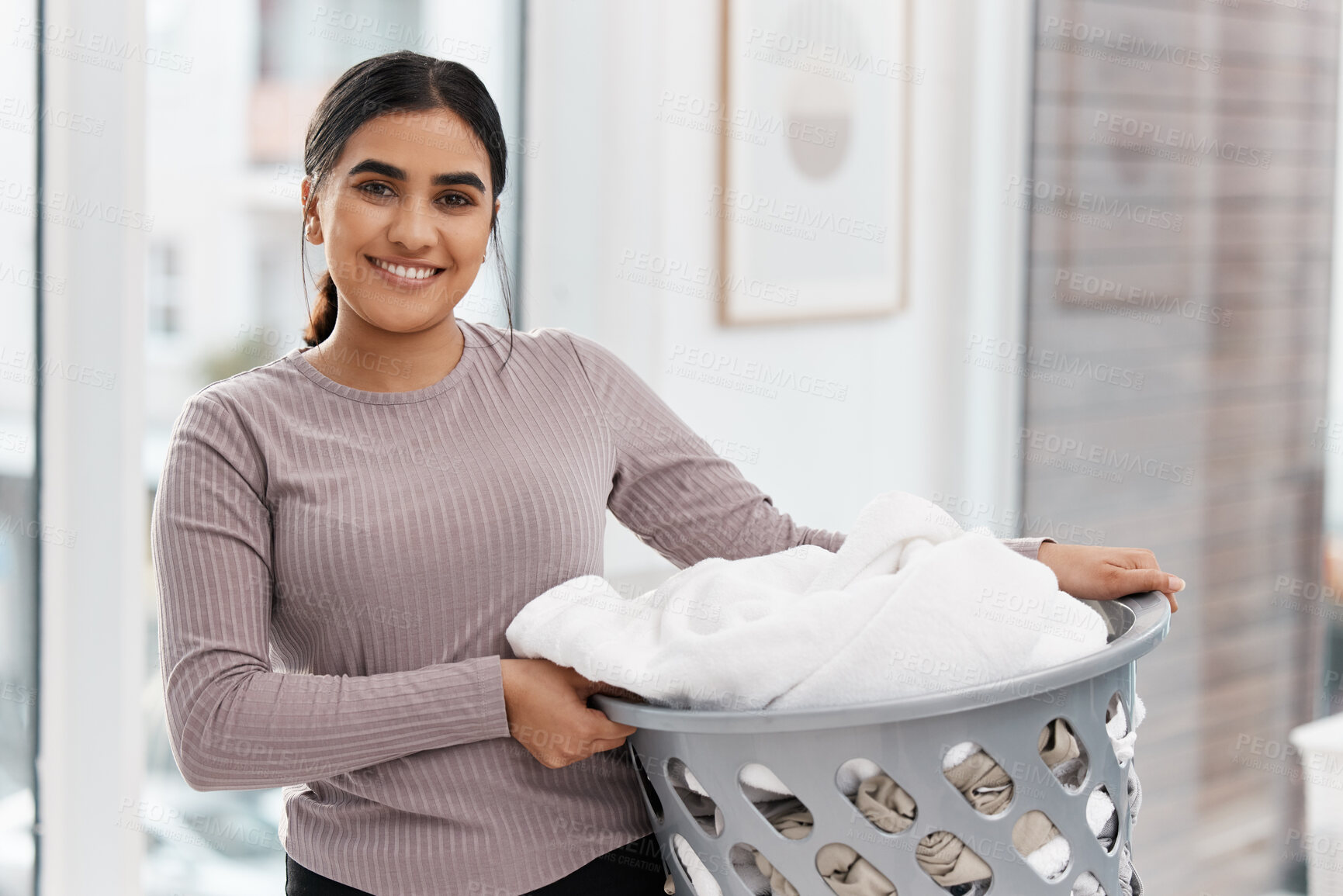 Buy stock photo Shot of a beautiful young woman doing the laundry at home