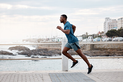 Buy stock photo Black man, runner and exercise outdoor on beach promenade for fitness, training or cardio workout. African athlete, person and running at sea for performance, health and wellness in nature with focus