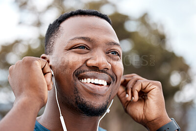 Buy stock photo Low angle shot of a sporty young man listening to music while exercising outdoors