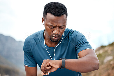Buy stock photo Shot of a sporty young man checking his wristwatch while exercising outdoors