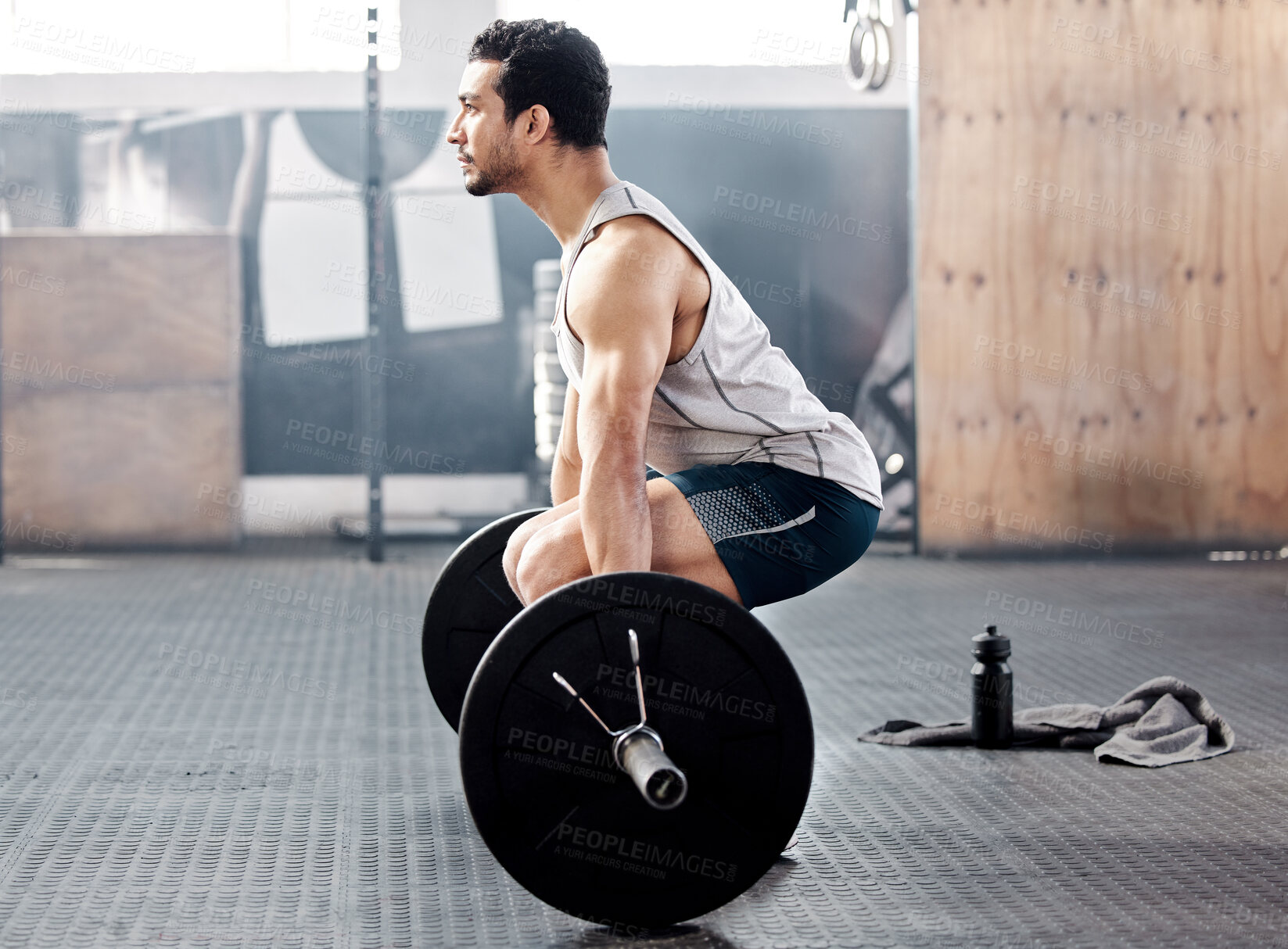 Buy stock photo Shot of a young man working out with a barbell in a gym