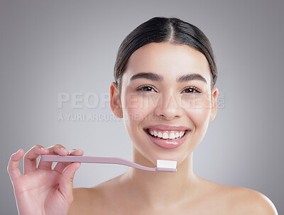 Buy stock photo Studio portrait of an attractive young woman brushing her teeth against a grey background