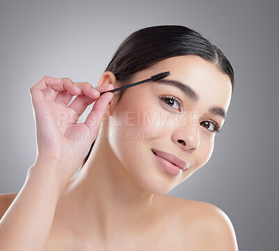 Buy stock photo Studio portrait of an attractive young woman apllying eyebrow makeup against a grey background
