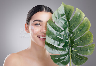Buy stock photo Studio portrait of an attractive young woman posing with a palm leaf against a grey background