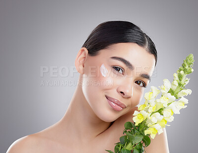 Buy stock photo Studio portrait of an attractive young woman posing with a bunch of flowers against a grey background