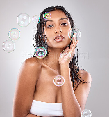 Buy stock photo Shot of bubbles floating over a beautiful woman in the studio