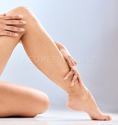 Buy stock photo Woman, legs and hands with epilation in skincare, grooming or hair removal waxing on a blue studio background. Closeup of female person, feet or beauty in laser treatment, cosmetology or dermatology