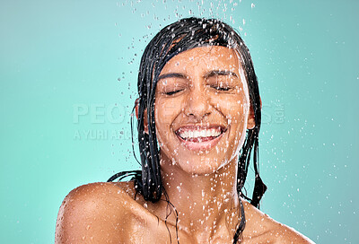 Buy stock photo Shower water, smile and a woman for wellness isolated on a blue background in a studio. Happy, clean and face of a young girl with happiness while showering, washing  or cleaning for grooming