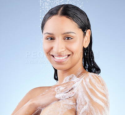 Buy stock photo Studio portrait of an attractive young woman taking a shower against a blue background