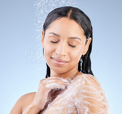 Buy stock photo Studio shot of an attractive young woman taking a shower against a blue background