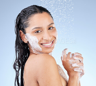 Buy stock photo Studio portrait of an attractive young woman taking a shower against a blue background