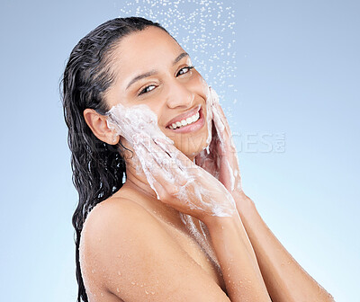 Buy stock photo Studio portrait of an attractive young woman taking a shower against a blue background