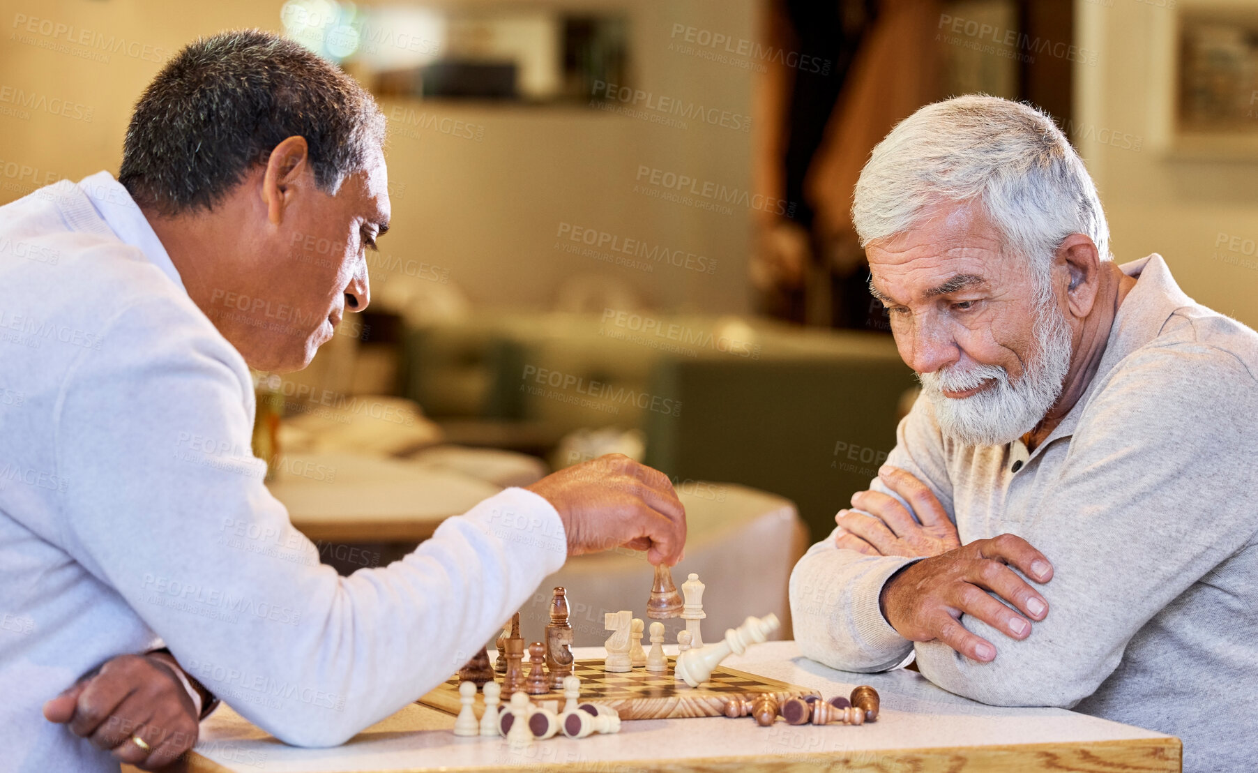 Buy stock photo Shot of two men sitting inside together and playing a game of chess