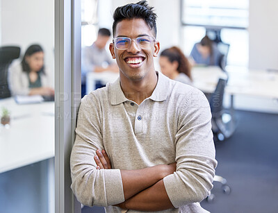 Buy stock photo Shot of a young businessman standing with his arms crossed in an office at work