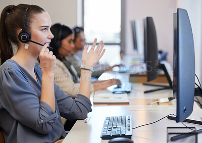 Buy stock photo Shot of a young call centre agent working in an office with her colleagues in the background