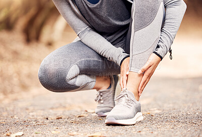 Buy stock photo Shot of an unrecognisable woman experiencing ankle pain while working out in nature